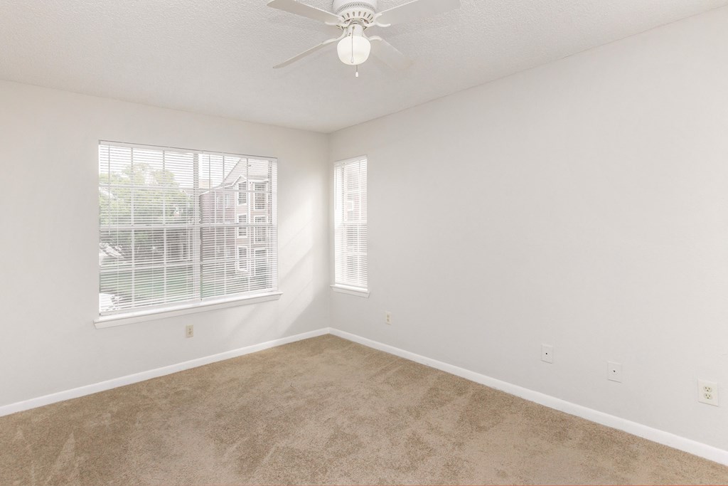 an empty bedroom with a ceiling fan and a window