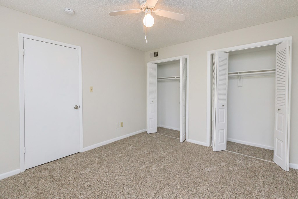 an empty living room with two closets and a ceiling fan