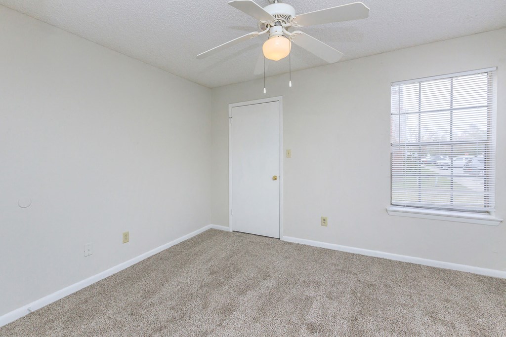 an empty bedroom with a ceiling fan and a window