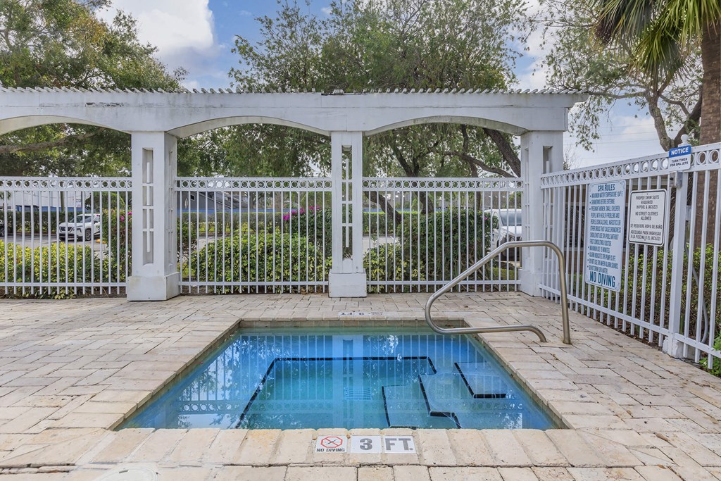 a swimming pool in front of a white fence with a pool