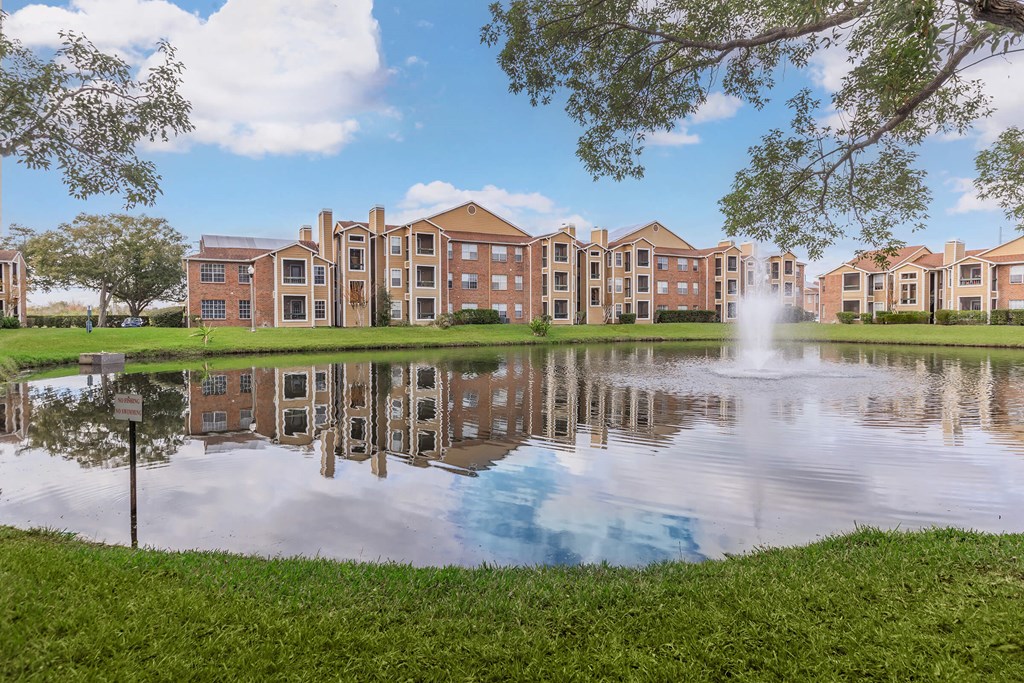 an apartment building overlooking a pond with a fountain