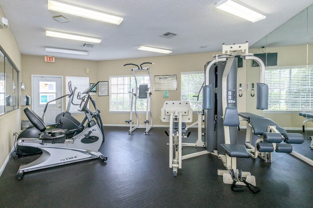 a gym with cardio equipment and weights on the floor