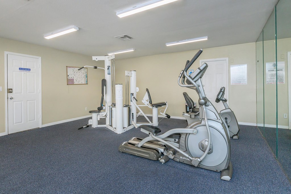 a gym with exercise equipment and mirrors on the wall