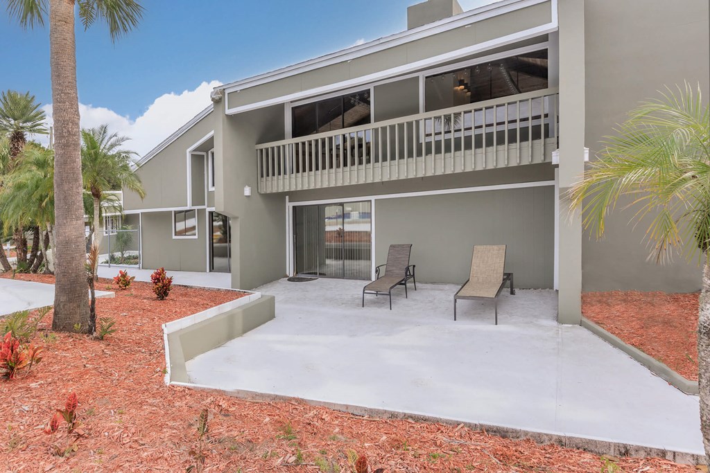 a patio with two chairs in front of a house