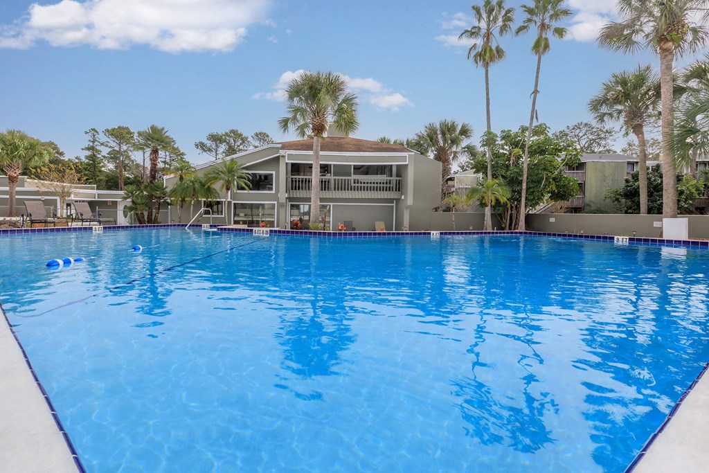 a large pool in front of a building with palm trees