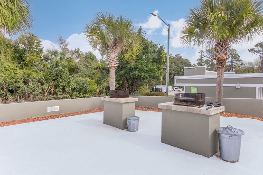 a patio with two gas grills and palm trees