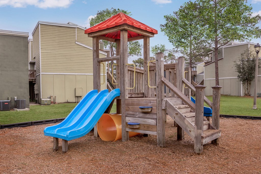 a playground with a blue slide and a wooden structure