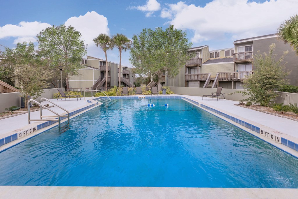 a large swimming pool with apartments in the background