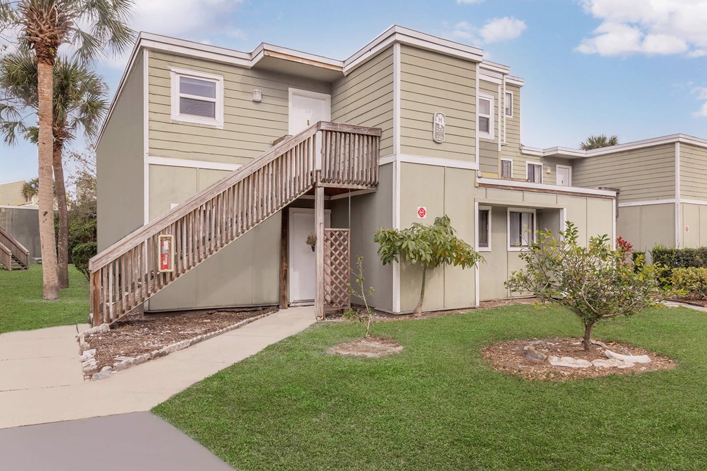 a yellow house with a wooden deck and a sidewalk