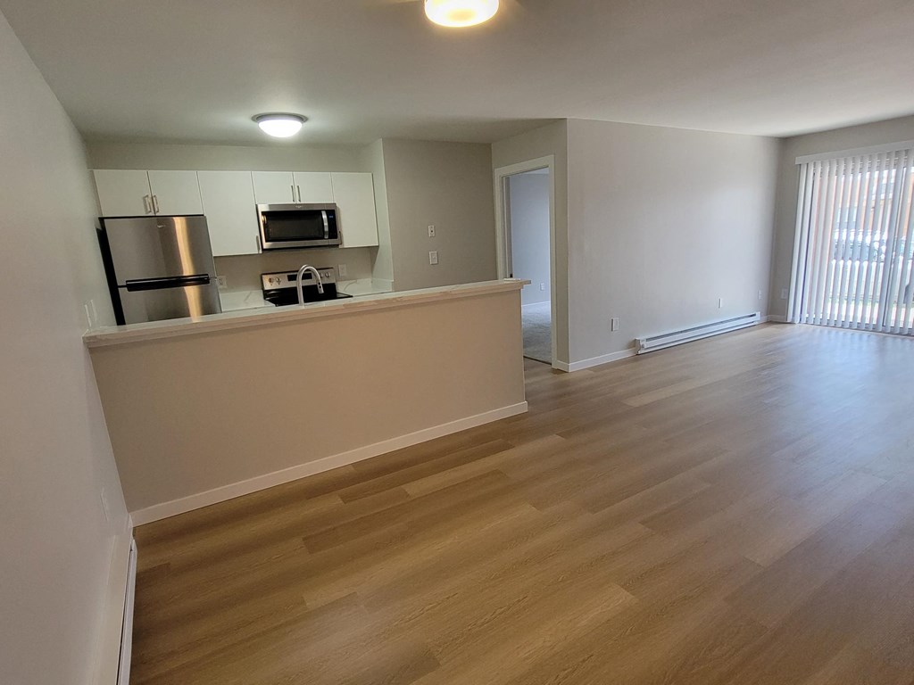 a kitchen and living room with wood flooring in an empty apartment