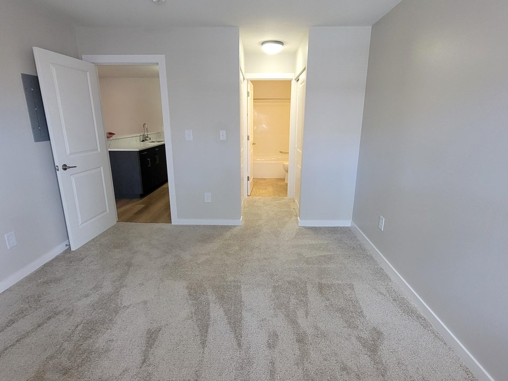 an empty living room with carpet and a door to a kitchen