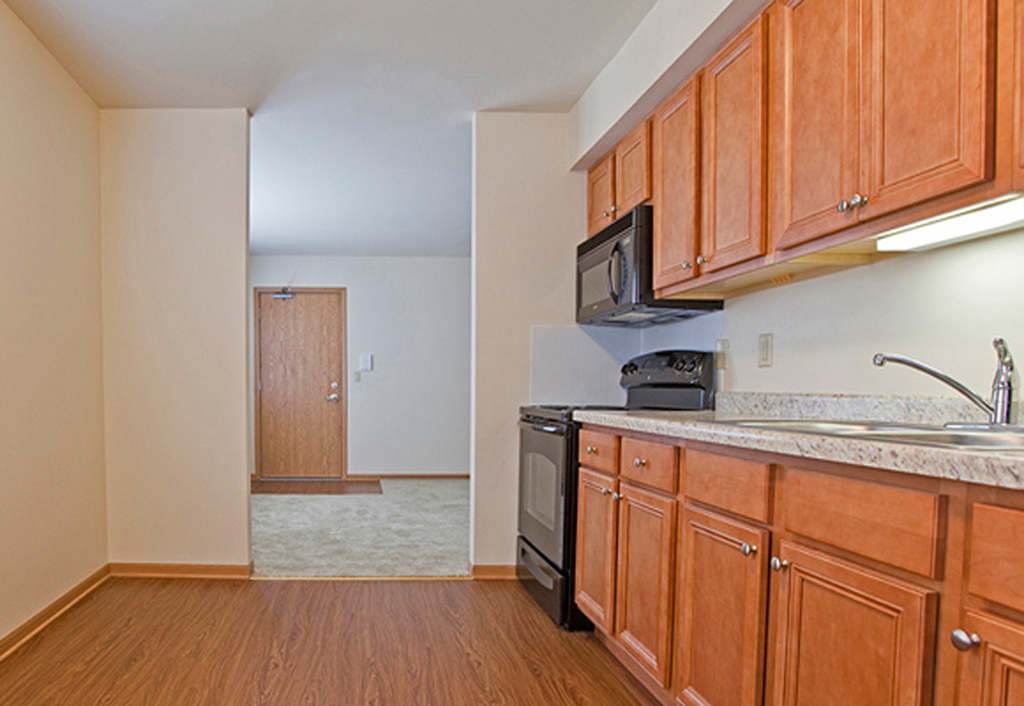 an empty kitchen with wooden cabinets and a black stove and microwave