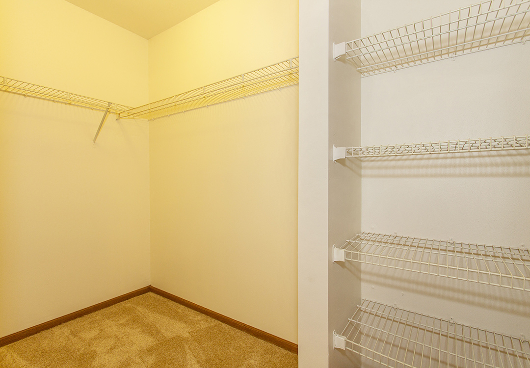 a walk in closet with empty shelves and a white wall