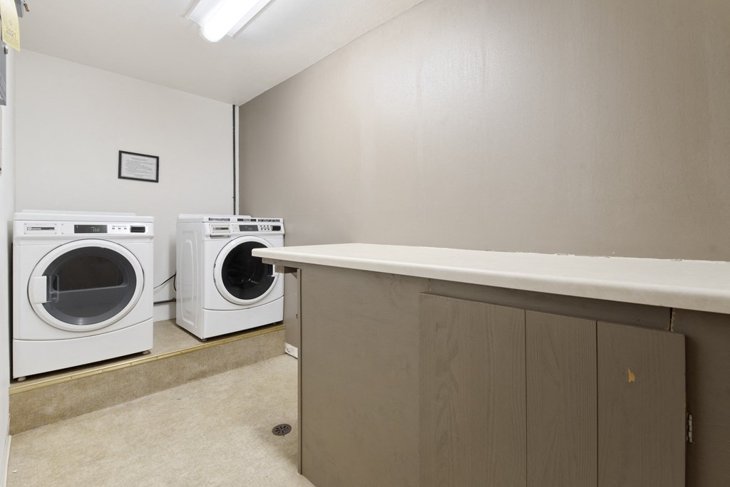 an empty laundry room with two washing machines and a counter