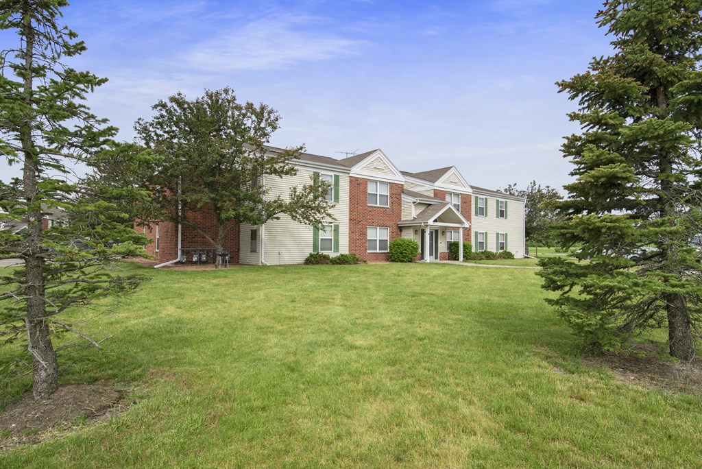 a large lawn in front of a house with trees