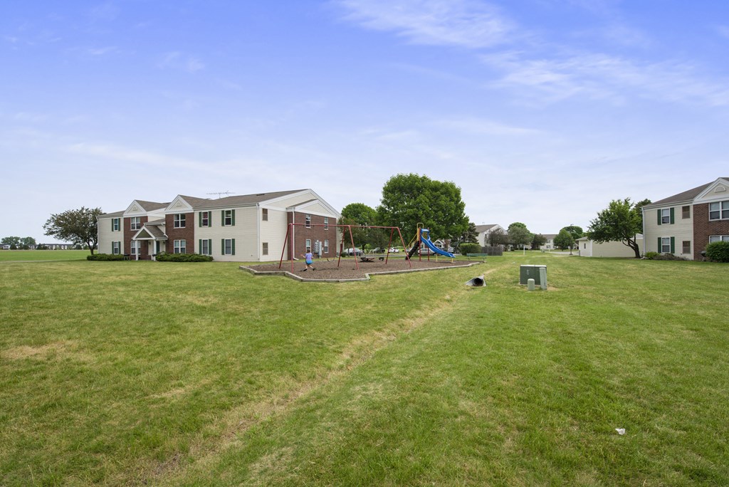 the view of a yard with a playground and houses in the background