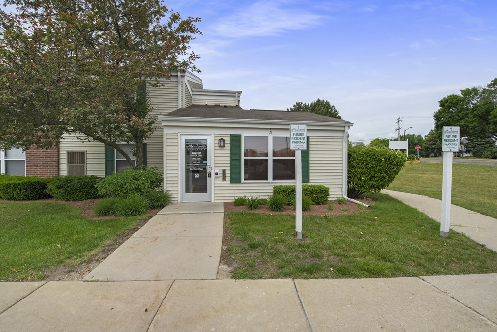 a small green and white house with a sidewalk in front of it