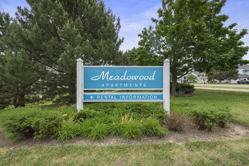 a sign in a grassy area with trees in the background