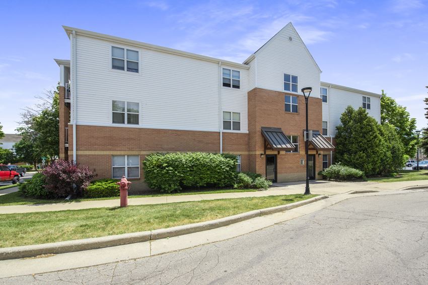 a brick and white apartment building with a red fire hydrant in front of it