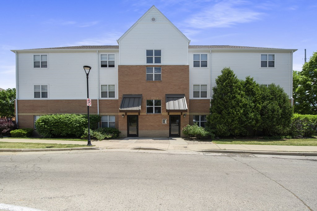 an apartment building with brick and white siding and a street light