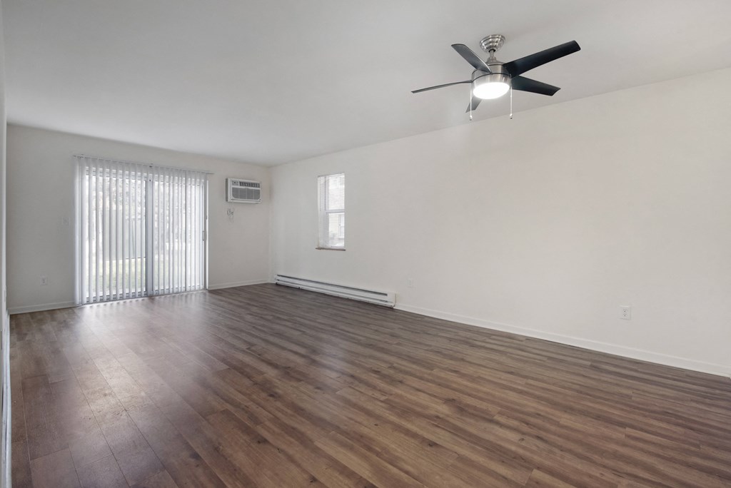 an empty living room with a ceiling fan and a window