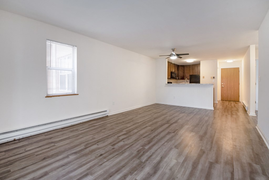 an empty living room with wood flooring and a ceiling fan