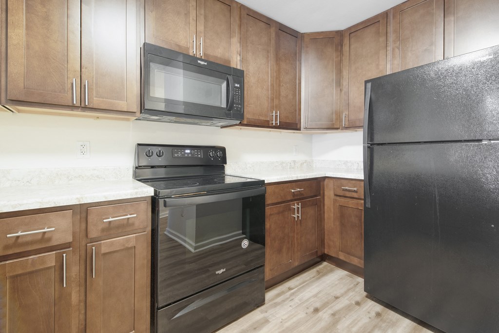an empty kitchen with black appliances and wooden cabinets