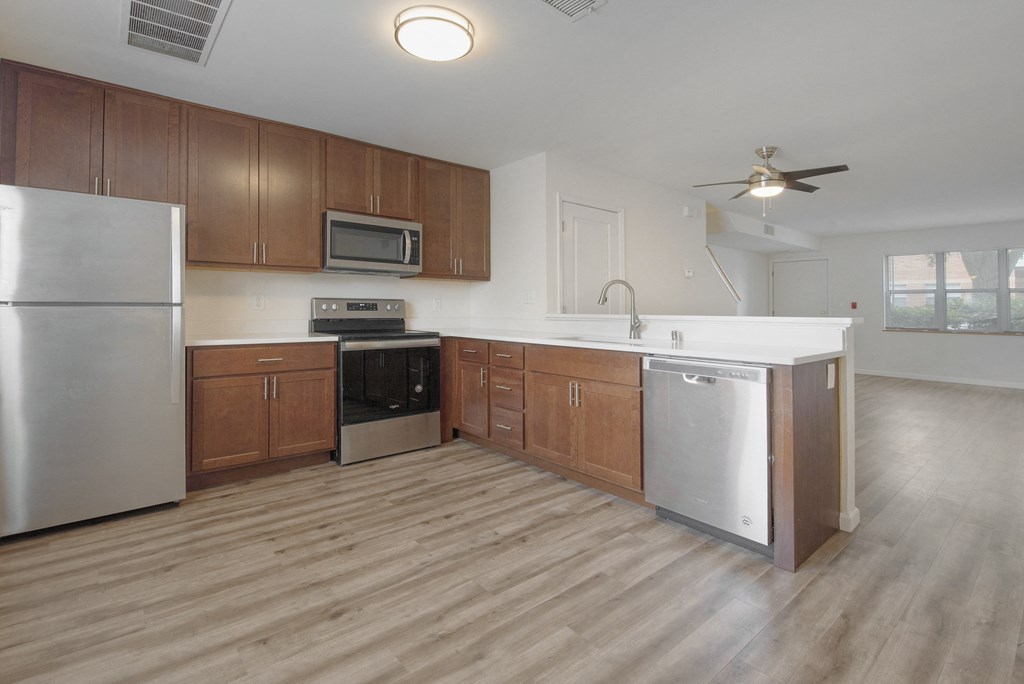 an empty kitchen with wooden cabinets and stainless steel appliances
