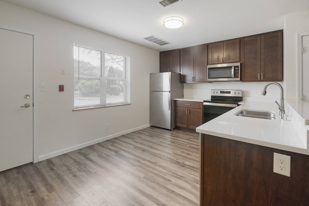an empty kitchen with wood flooring and a white counter top