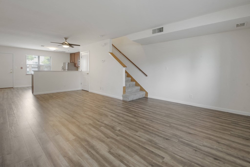 the living room and kitchen of an empty house with white walls and wood floors