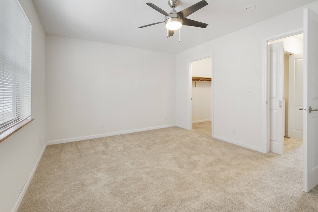 an empty living room with a ceiling fan and a closet
