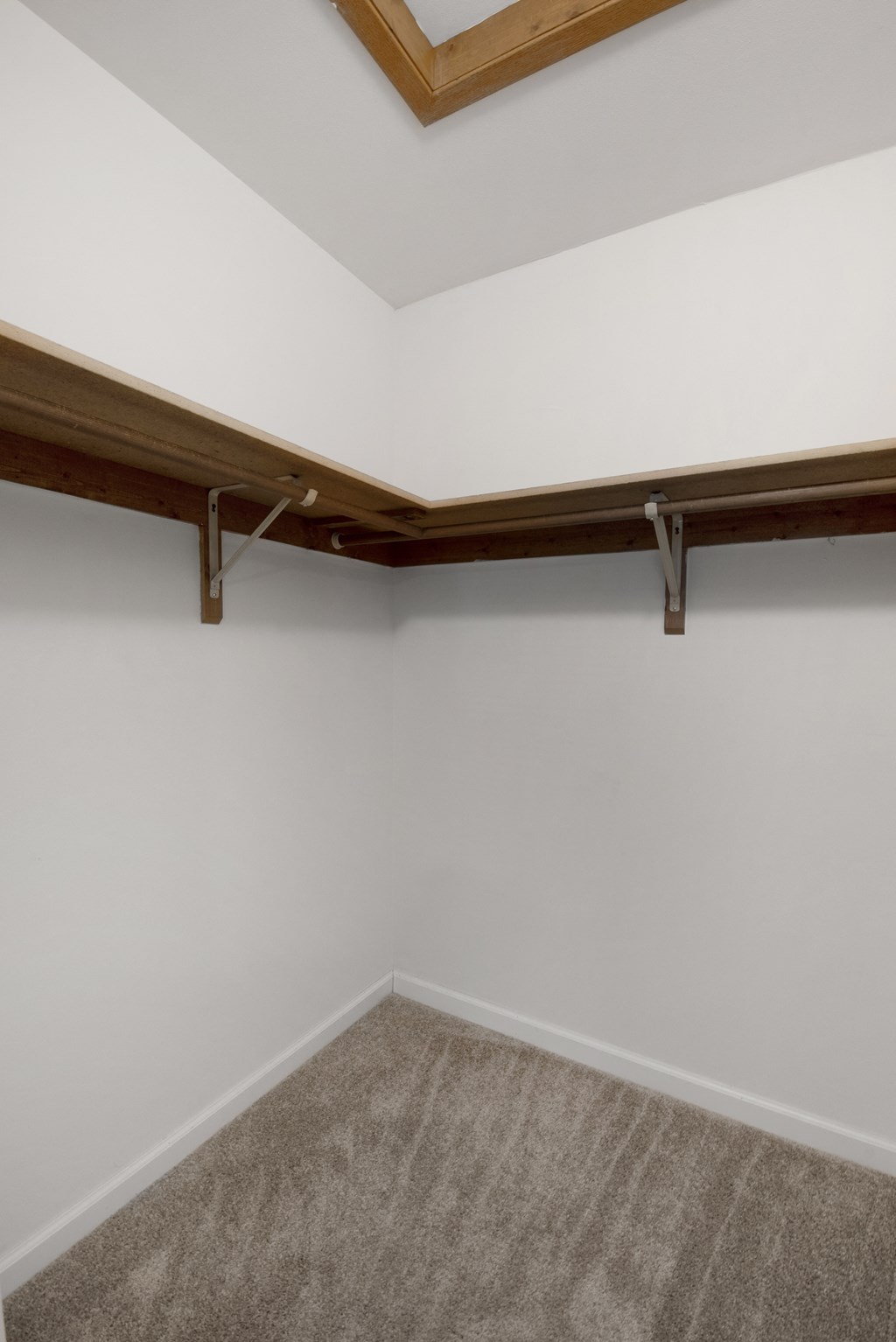 a room with a carpet and a white wall and a wooden shelf on the ceiling
