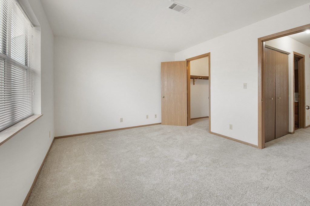 an empty living room with a door to a closet and a window