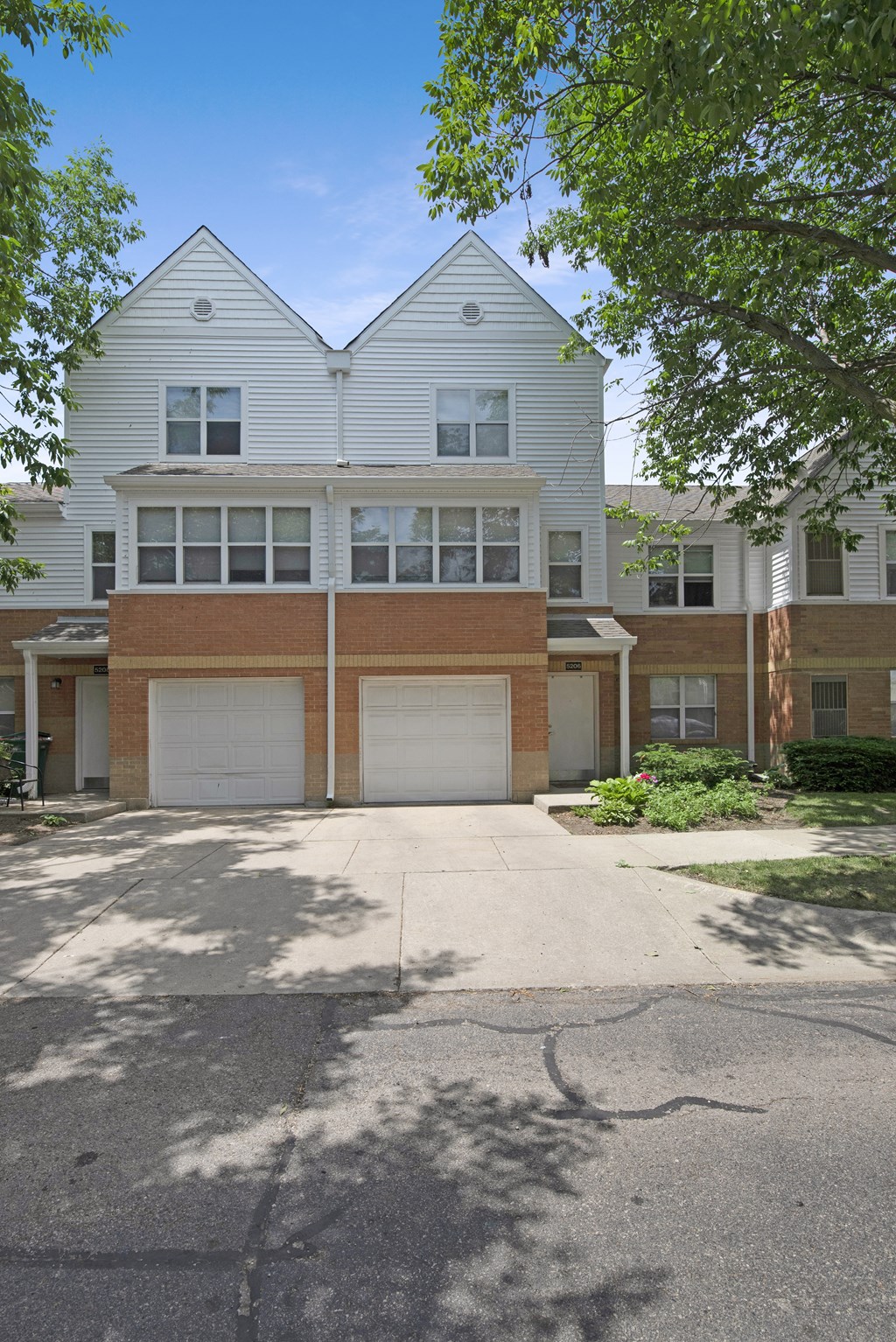 a white and brick house with two garage doors