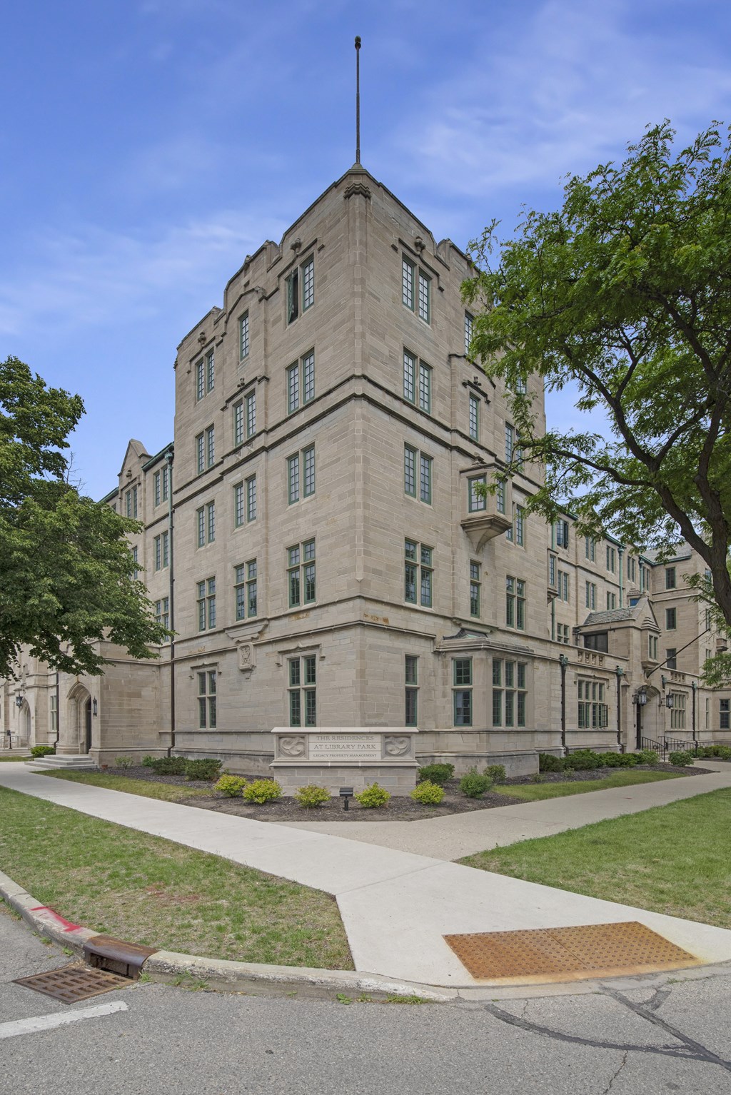 a tall stone building with a flag on top and a sidewalk in front