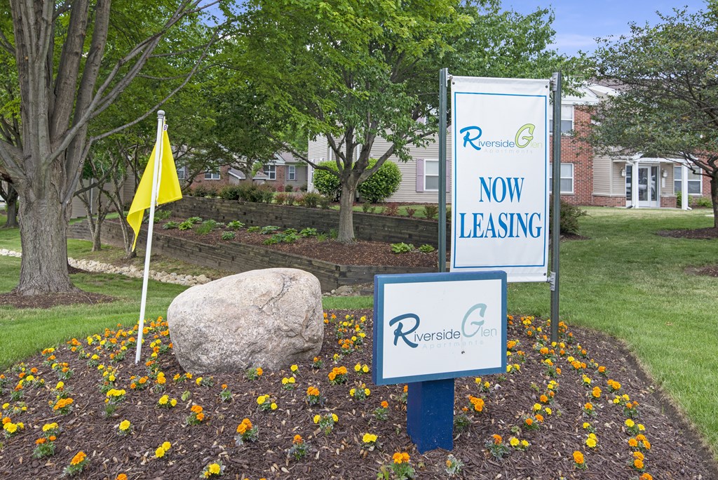 a now leasing sign and a yellow flag in a garden