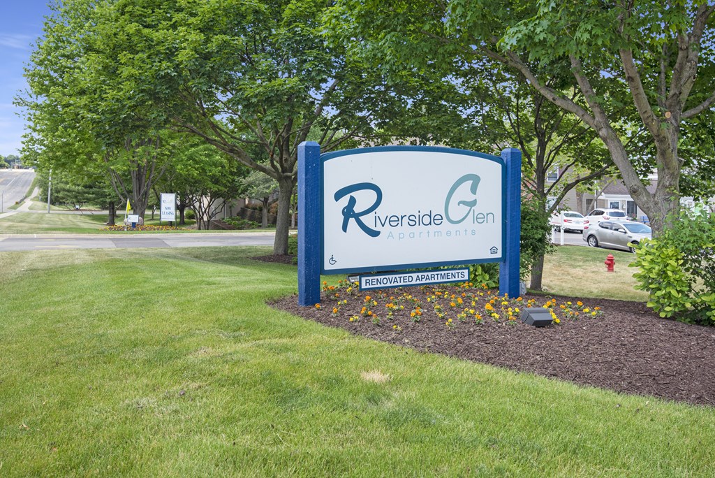 a blue and white sign in the middle of a park