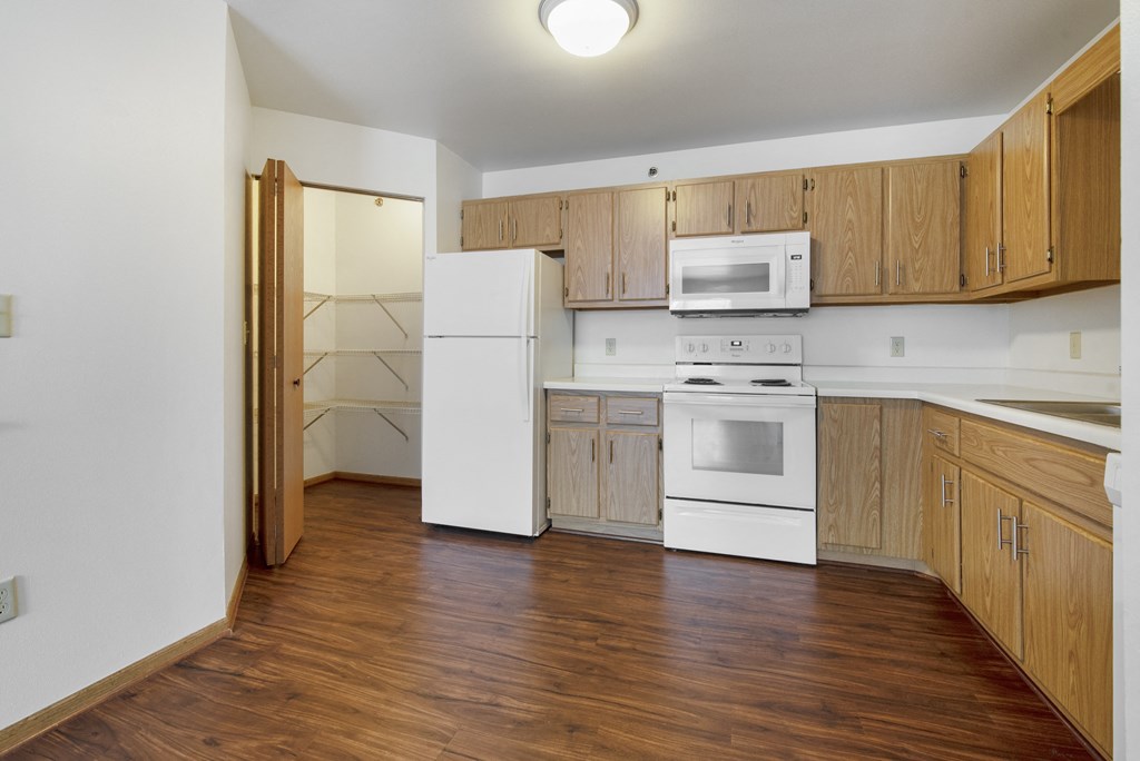 an empty kitchen with white appliances and wooden cabinets