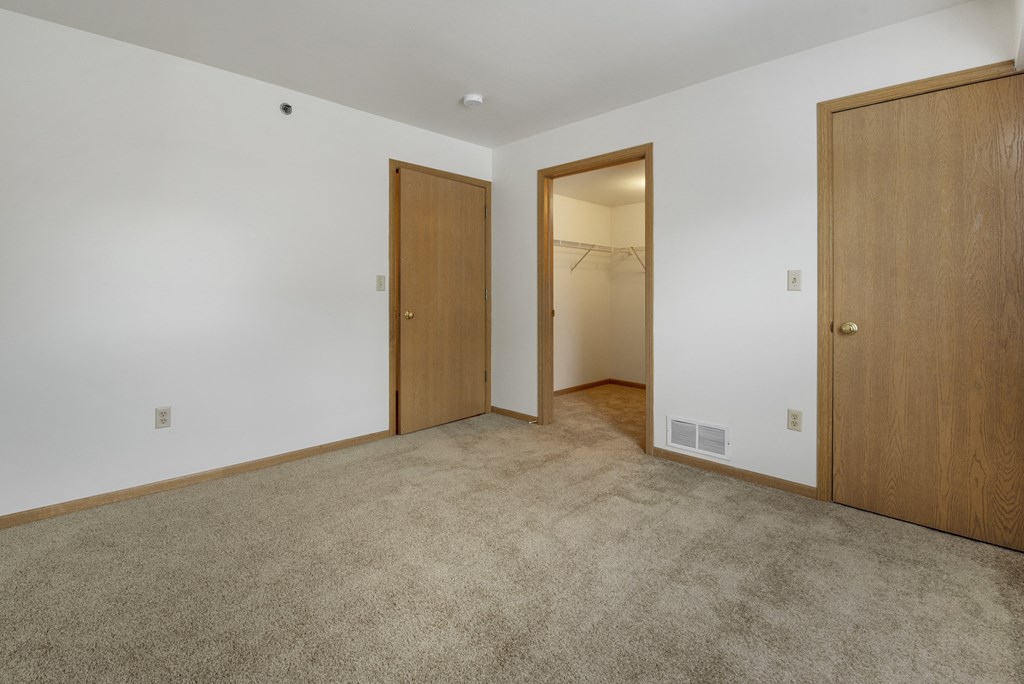 a bedroom with a carpeted floor and two doors to a closet