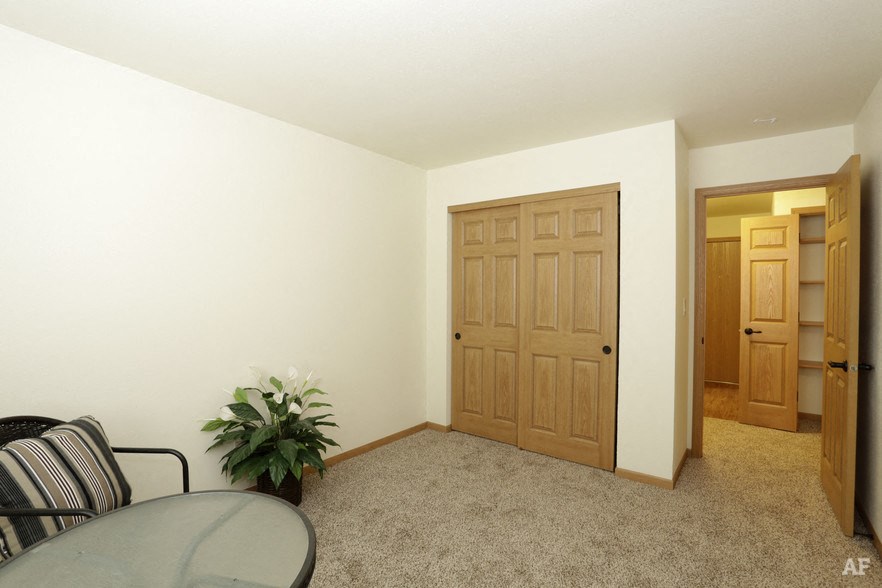 an empty living room with a table and a door to a bedroom