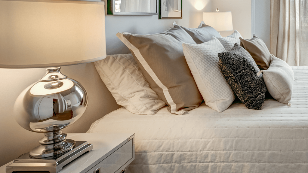 a bed with pillows and a lamp on top of it