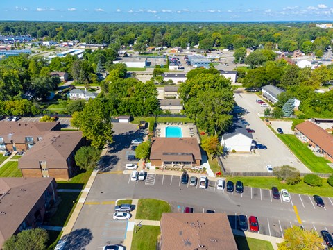 A bird's eye view of a residential area with a swimming pool and parked cars.