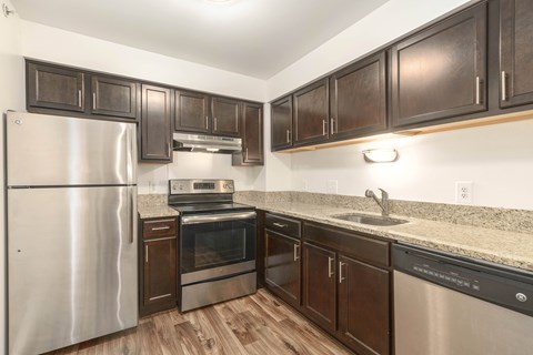A kitchen with a stainless steel refrigerator and wooden cabinets.