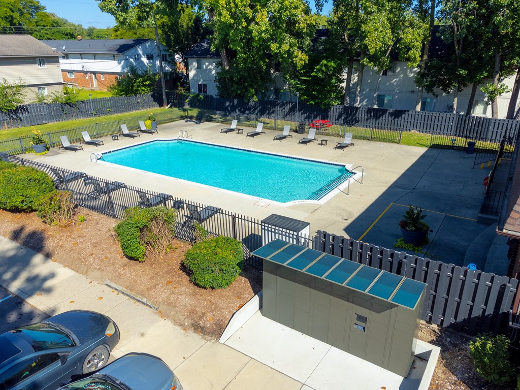 Open and heated pool space with lounge chairs and 24/7 secured package lockers at Knottingham Apartments in Clinton Township, MI