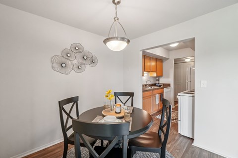 A dining room with a table set for two and a chandelier hanging from the ceiling.