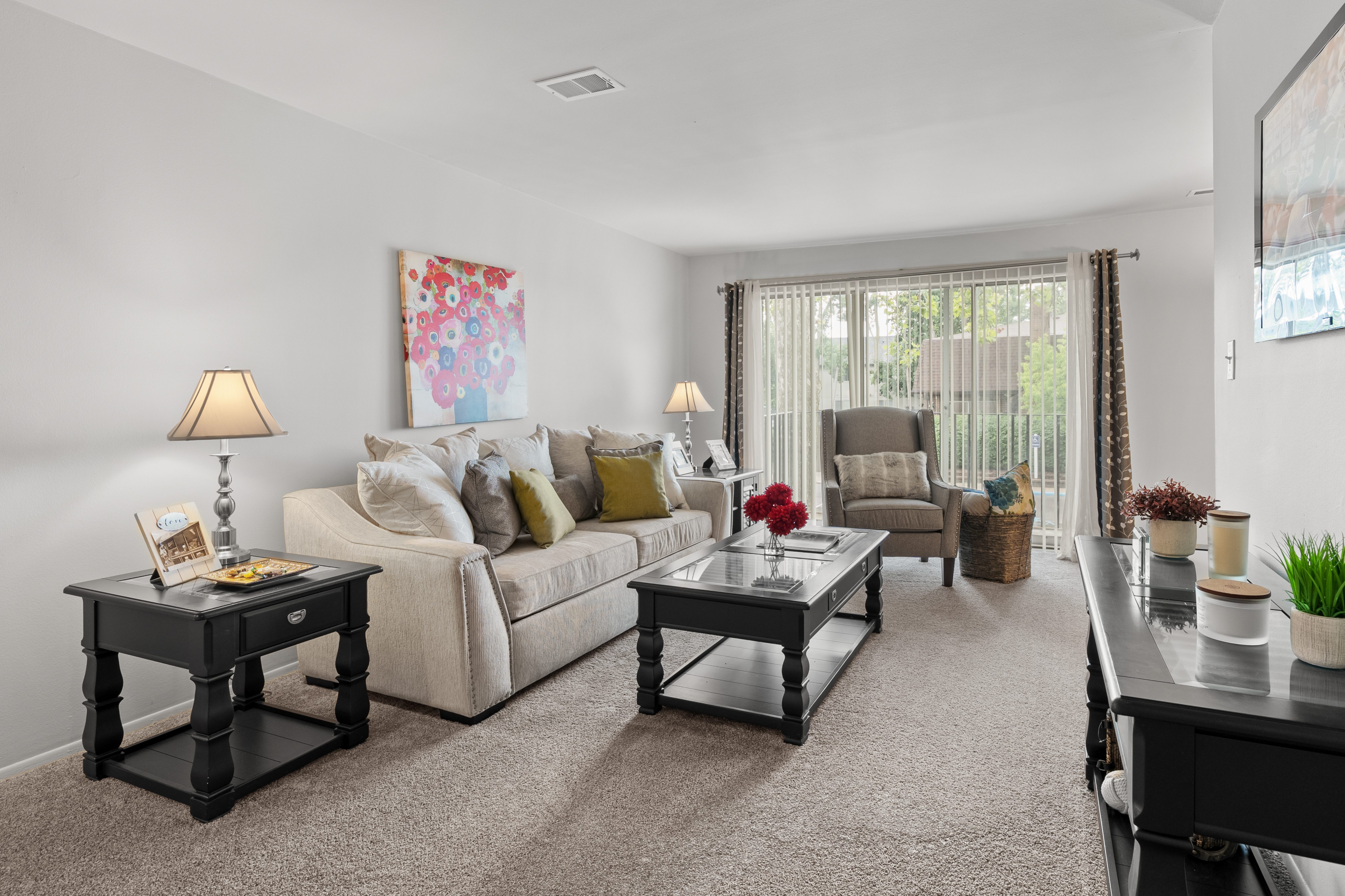 A living room with a white couch, a coffee table, and a painting on the wall.
