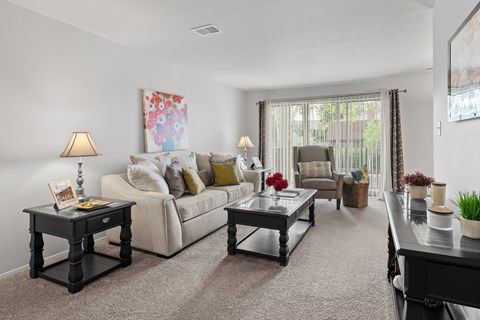 A living room with a white couch, a coffee table, and a painting on the wall.