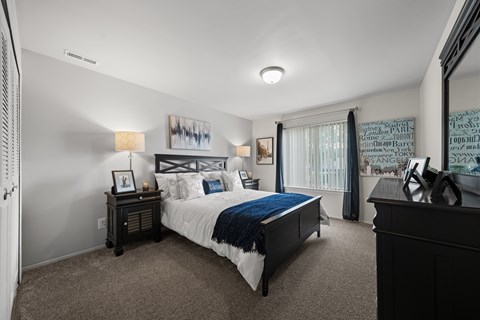 A bedroom with a bed, nightstand, and a painting on the wall.
