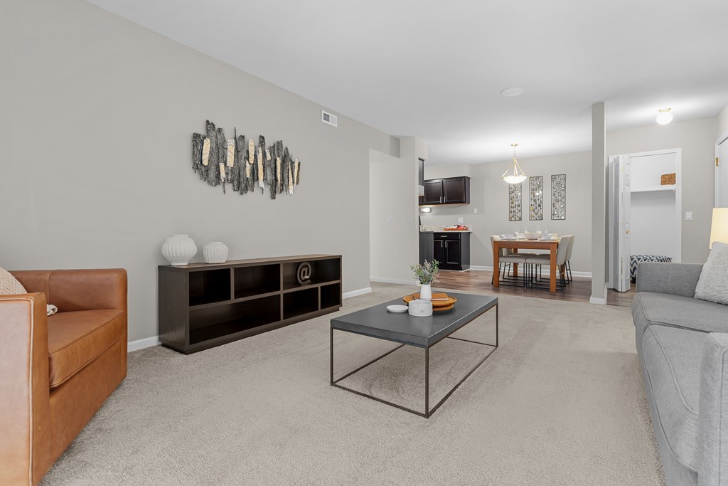 Open concept Living-Dining Area with natural lighting at Lakeside Village Apartments Clinton Township, MIroom with a brown leather chair, a glass coffee table, and a wall art.