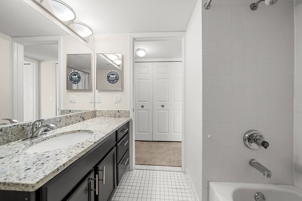 Modern bathroom with large vanity mirror and tub/shower at Lakeside Village Apartments in Clinton Township, MI